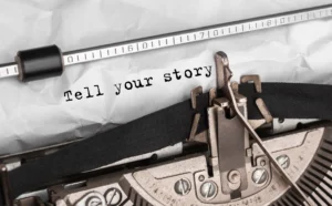 Close-up of a typewriter typing "Tell your story" on crumpled paper. Vintage aesthetic evokes creativity and personal expression. Canadian Ghostwriters