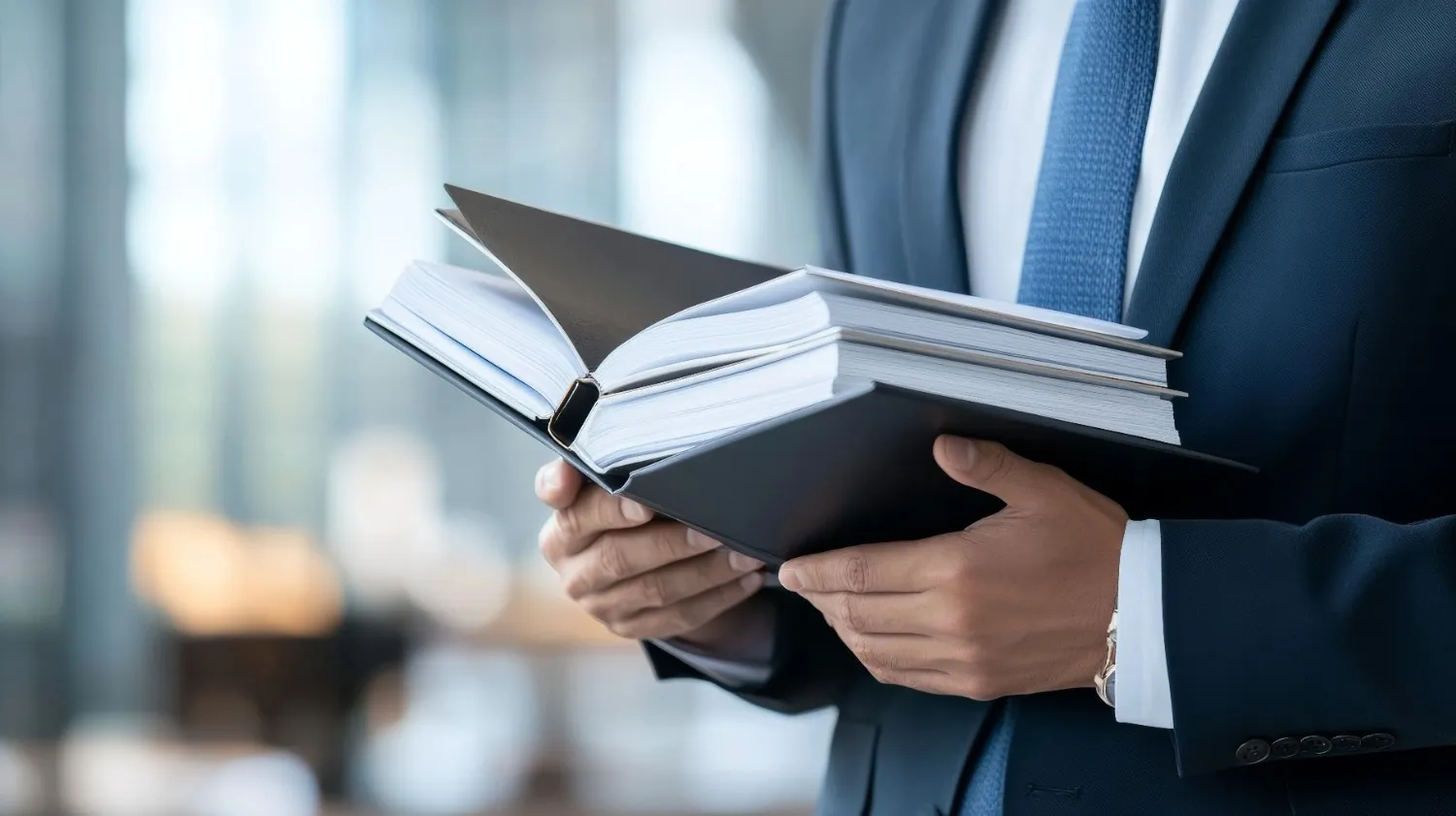 businessman-holding-open-black-binder-modern-office-environment