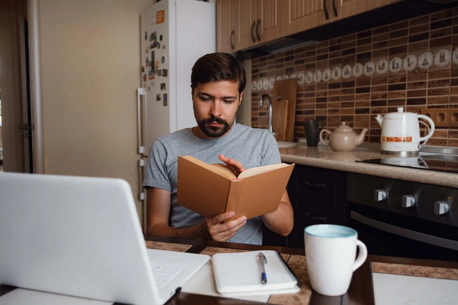 attractive-young-hipster-man-focused-reading-book-home-office canadianghostwriters