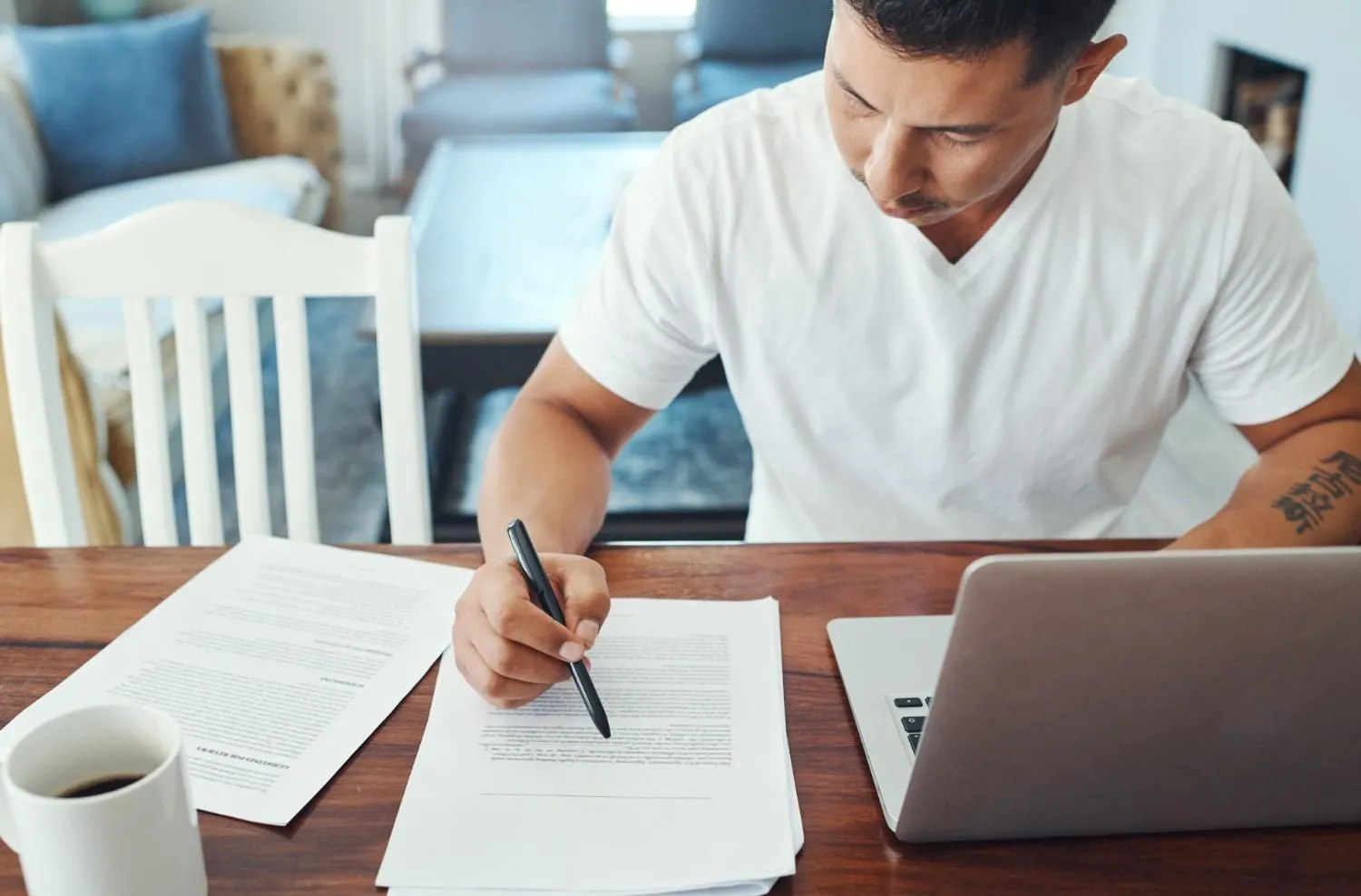 remote-work-laptop-man-with-documents-table-review-sentence-structure-editing-proofreading-freelance-person-check-grammar-verify-references-format-guidelines-home canadianghostwriters