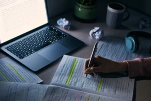 student-hands-writing-notes-night-with-laptop-research-education-internet-project-closeup-college-people-reading-write-homework-dark-desk-maths-studying-learning canadianghostwriters