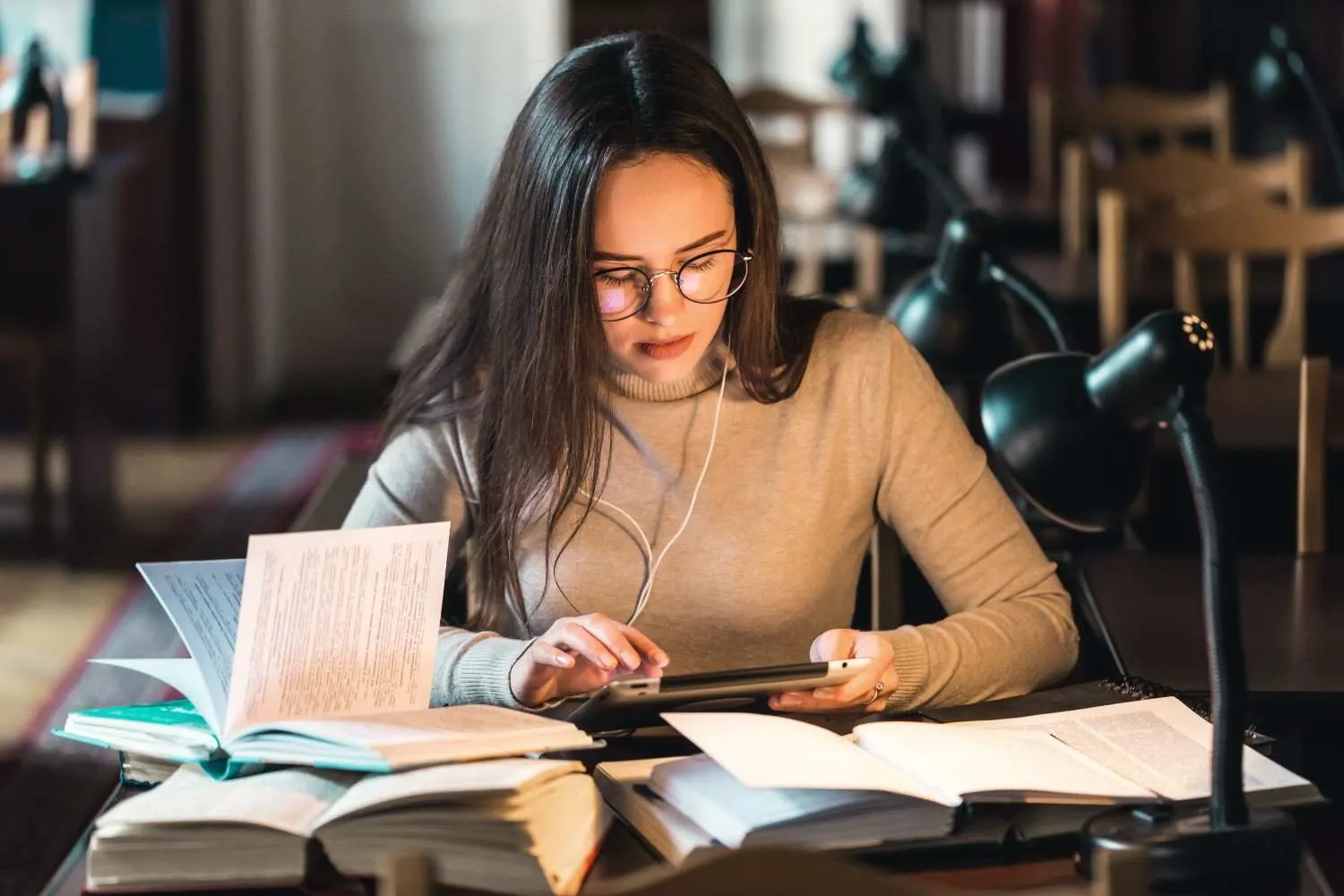 pensive-long-haired-teenage-girl-studying-table-library-using-tablet-books- canadianghostwriters